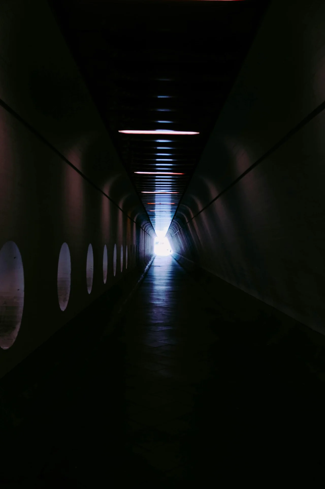 Dark tunnel with a distant light source, signaling constrained optionality and directional urgency.