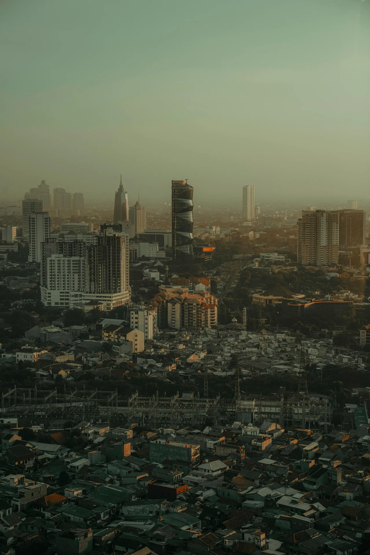 Hazy city skyline at dusk, indicating ambient pressure, atmospheric opacity, and structural scale under muted visibility.