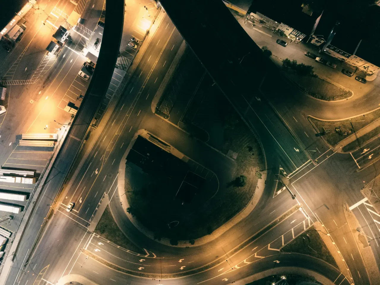 Top-down urban overpass and road geometry at night, suggesting route selection, pressure convergence, and operating flow.