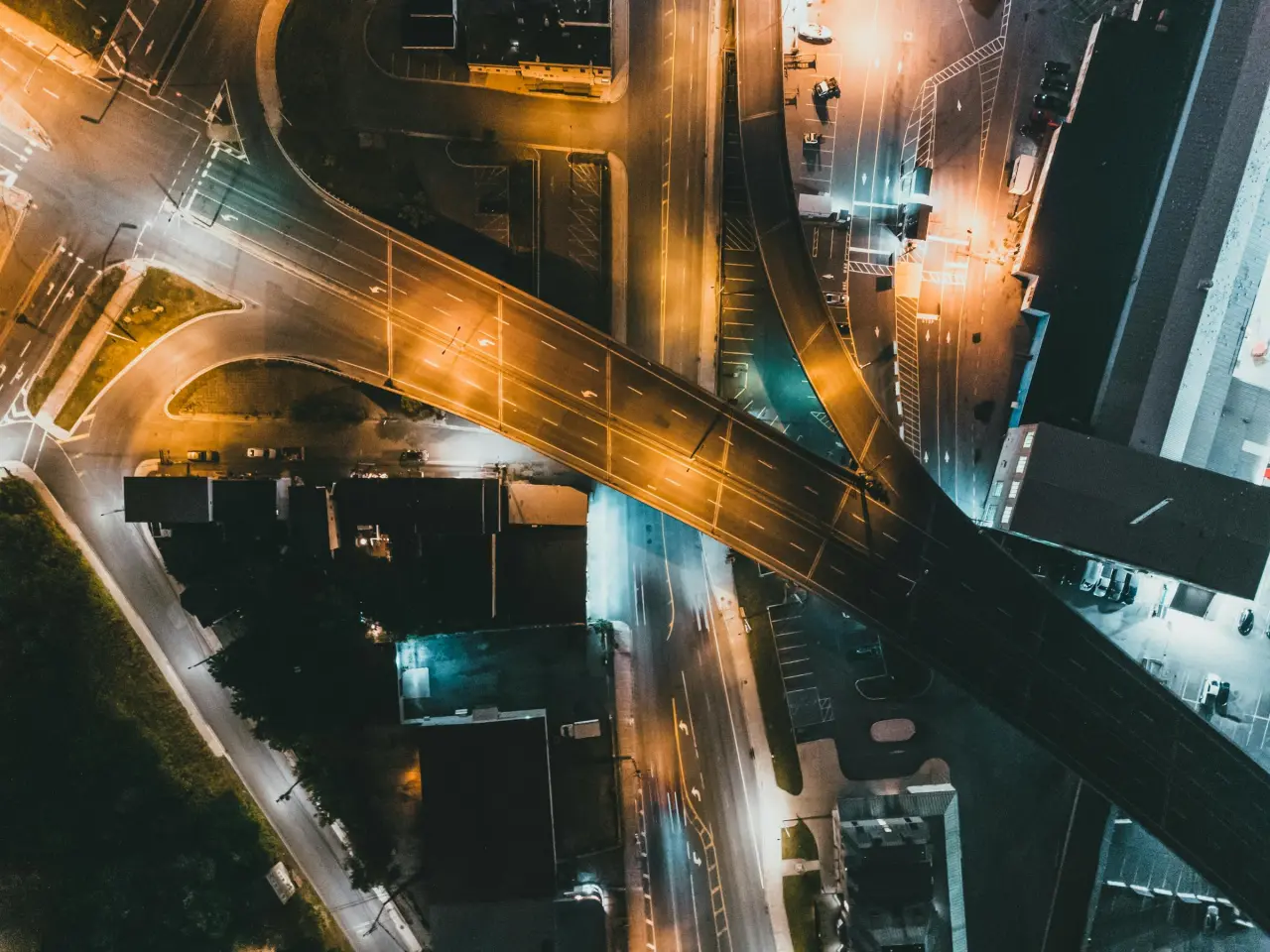 Aerial night road network with bridges, light trails, and intersecting paths, representing pressure-front interaction and diagnostic flow.
