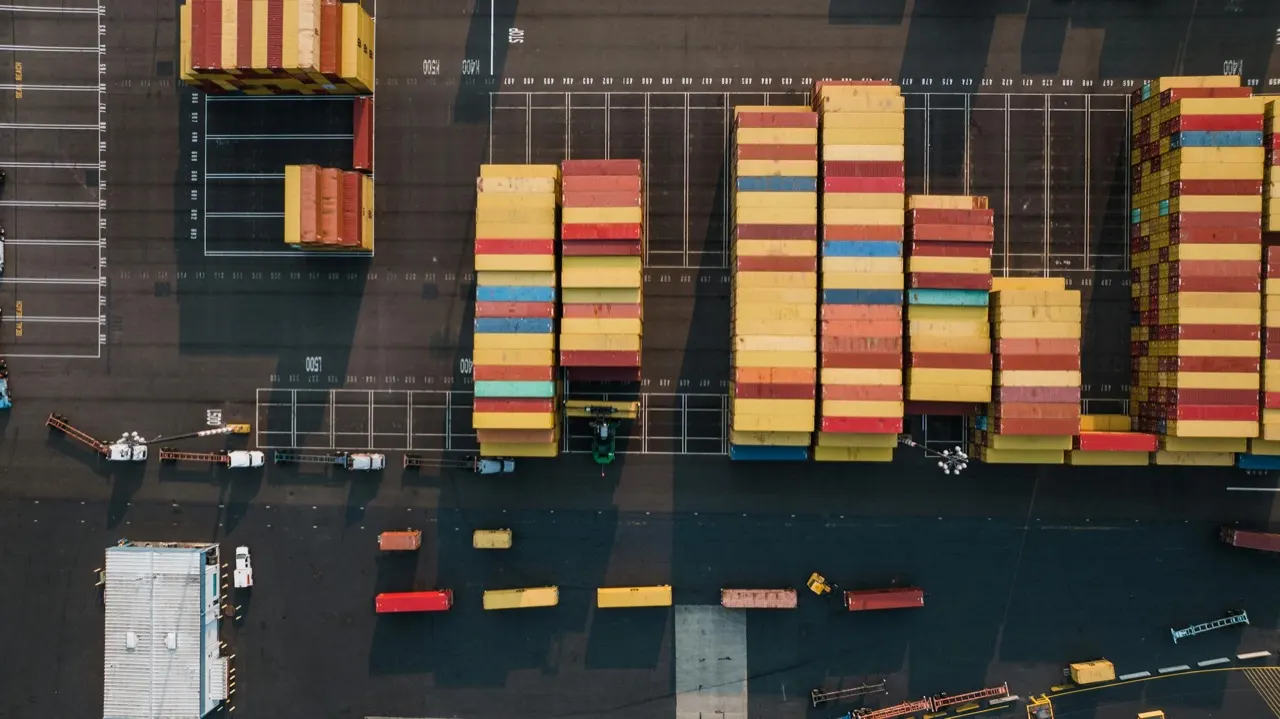 Aerial cargo container yard with clear operating lanes and storage geometry, expressing system-scale constraint and coordinated throughput.