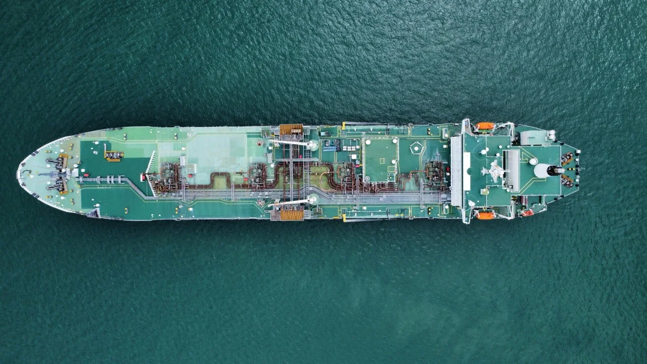 Top-down view of a tanker crossing open water, emphasizing maritime concentration and corridor dependence.
